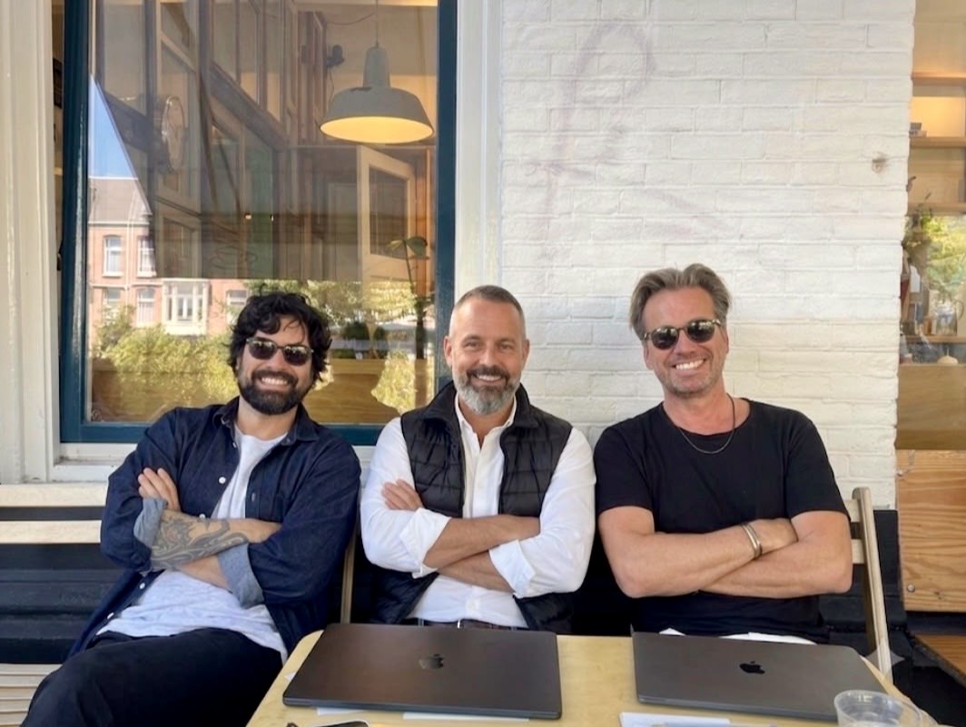 HolaSwitch founders Loïc, Mitchell and Djordi sitting together outside a café